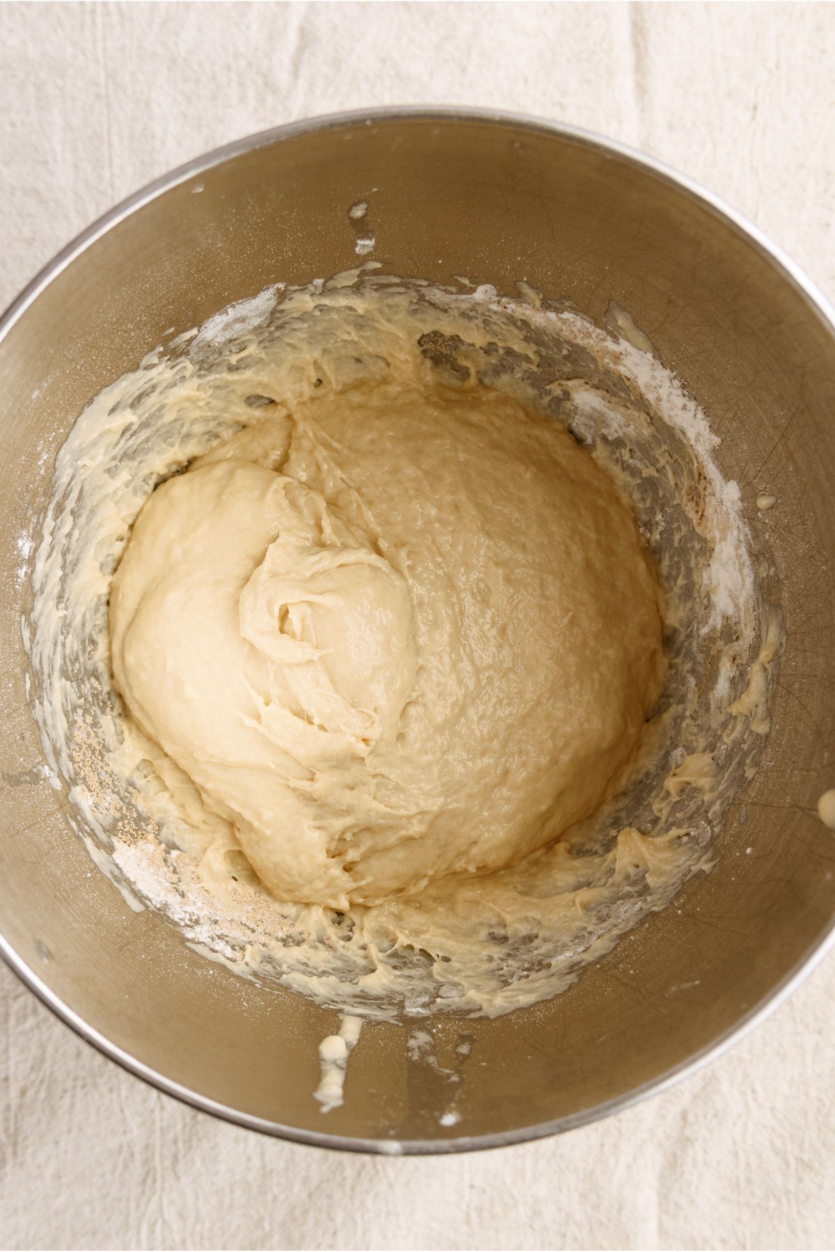 Bread dough rising in a metal mixing bowl.