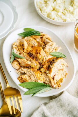 Shredded Turkey breast on a white serving platter. A gold serving spoon and fork on the side.