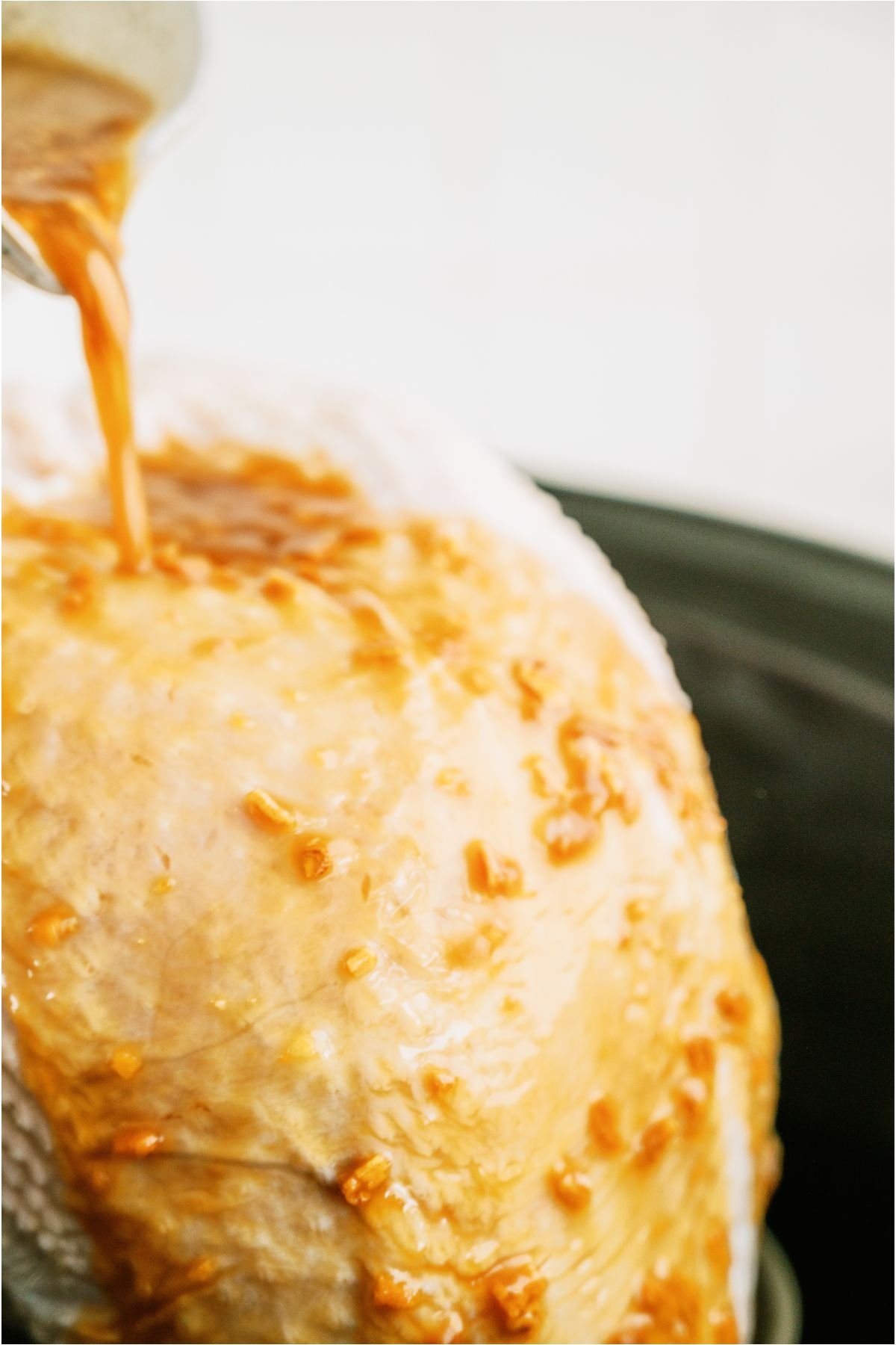 Pouring onion soup mixture on top of raw turkey breast in slow cooker.