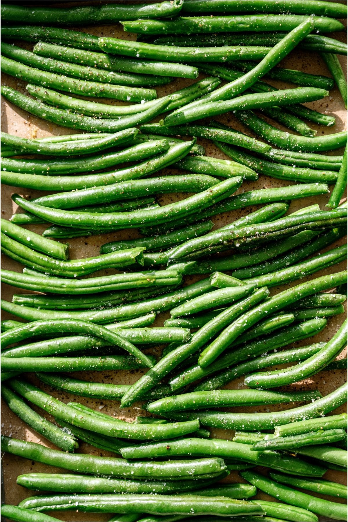 Fresh Green beans seasoned, on a baking sheet.