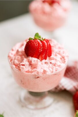 5 Minute Strawberry Jello Salad in a parfait dish with a sliced strawberry on top.