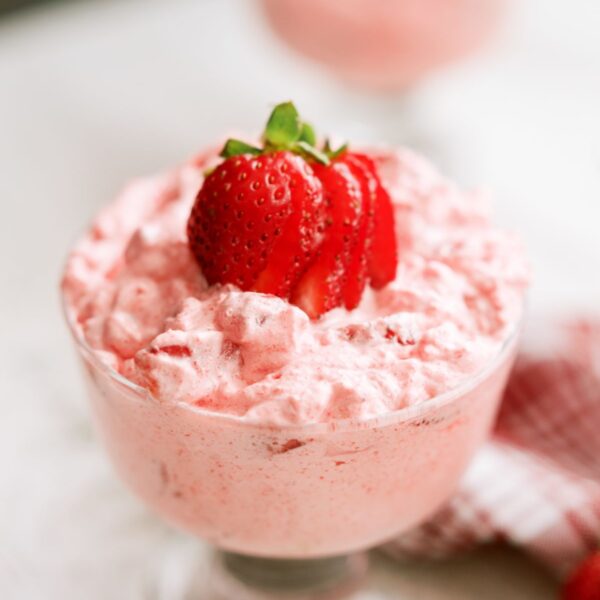 5 Minute Strawberry Jello Salad in a parfait dish with a sliced strawberry on top.