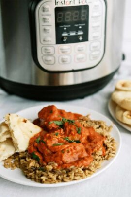 Chicken on a plate with naan bread. With an Instant Pot and a plate of naan bread in the background.