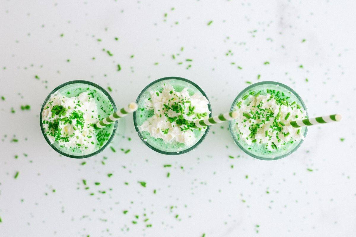 Top view of 3 glasses filled with Copycat McDonald’s Shamrock Shake and topped with whip cream and sprinkles.