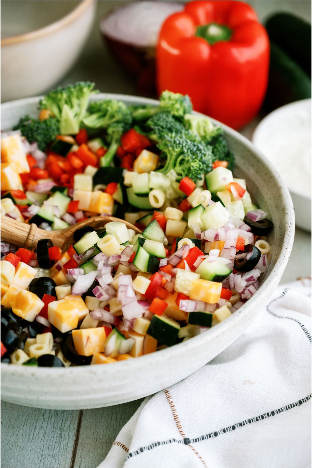 Ingredients for pasta salad mixed together in a large serving bowl.