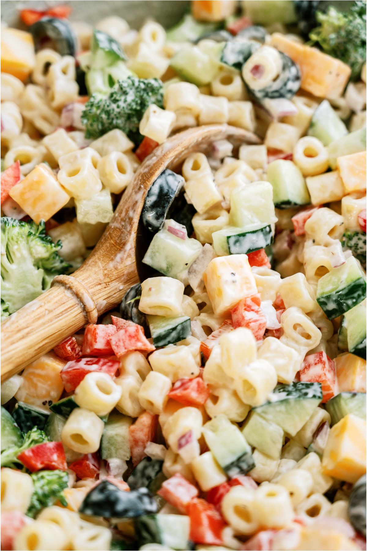 Close up view of Creamy Pasta Salad with a wooden serving spoon.