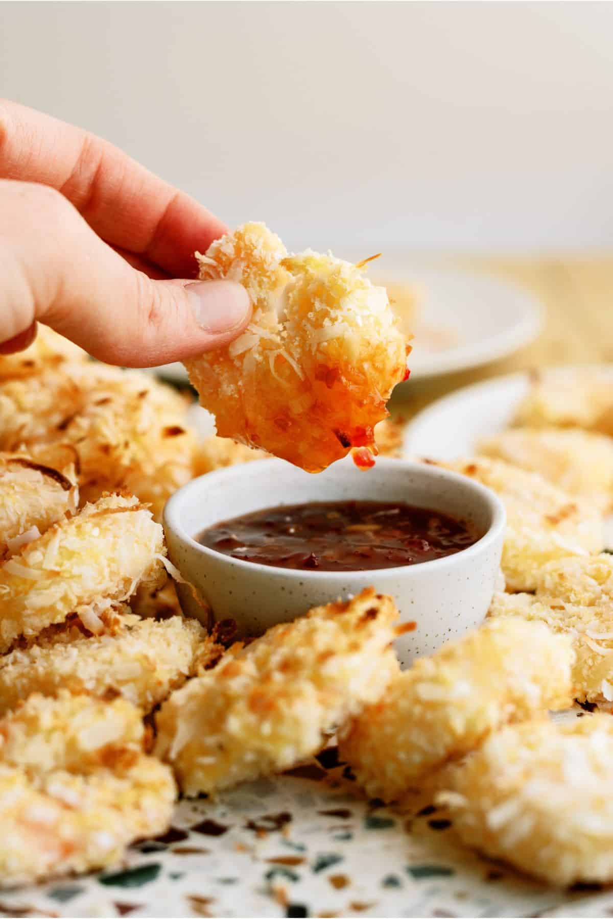 Dipping an Air Fryer Coconut Shrimp in chili sauce