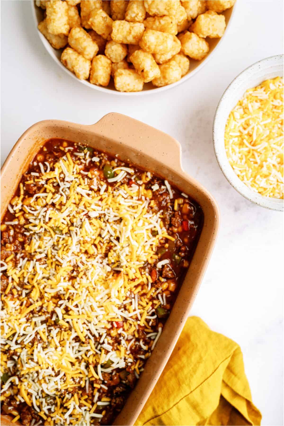 Shredded cheese on top of ground beef mixture in casserole dish