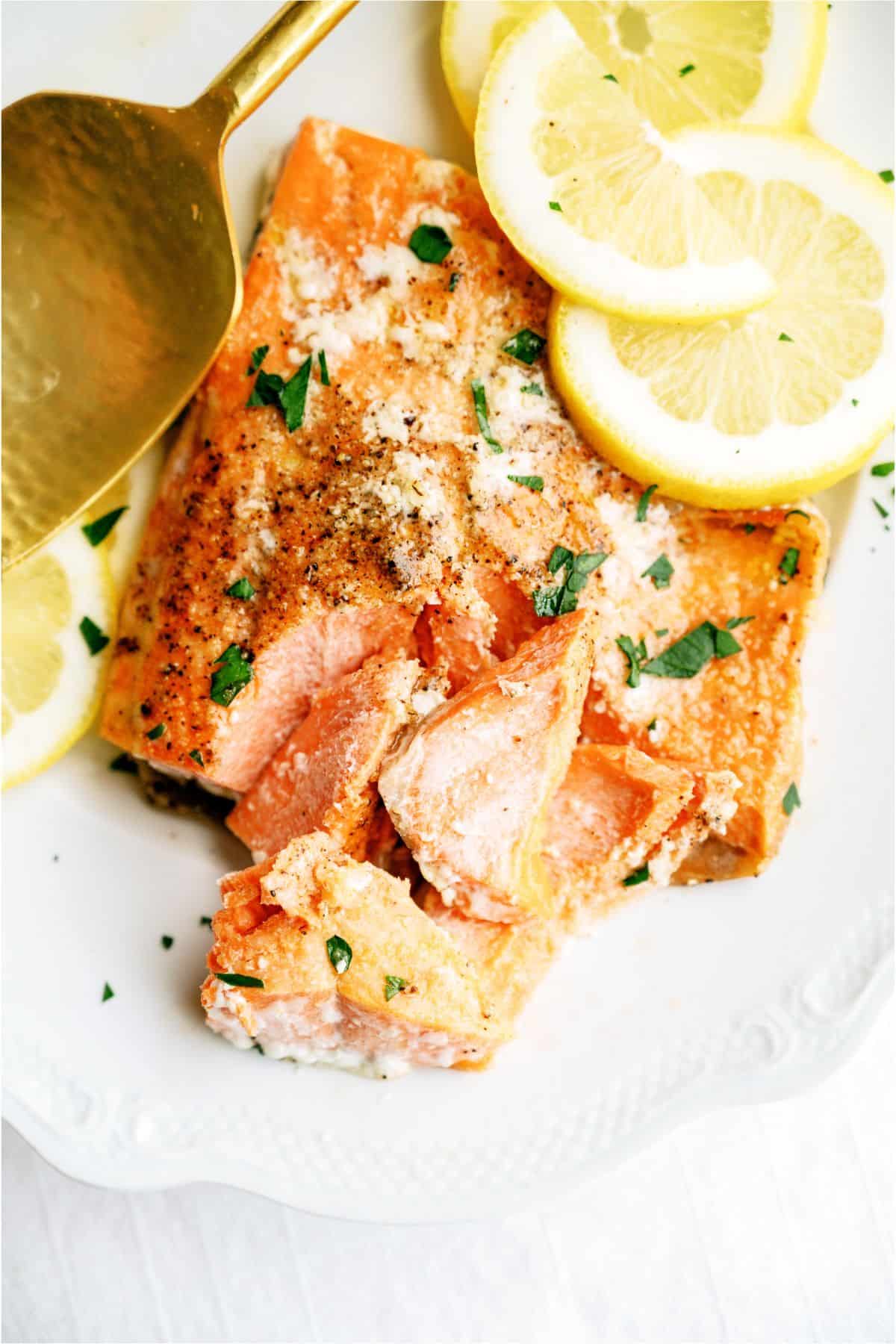 Baked Salmon filet on a plate flaked with a fork and fresh lemon