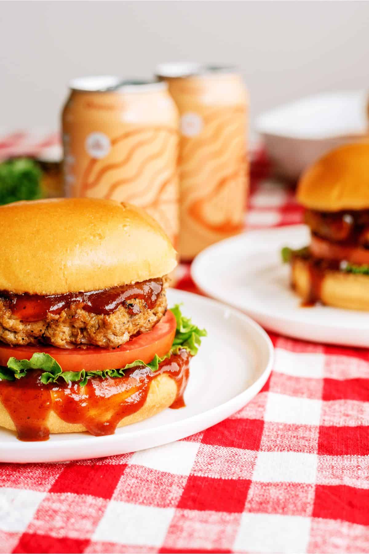 Juicy BBQ Turkey Burgers on plates with soda cans in the background