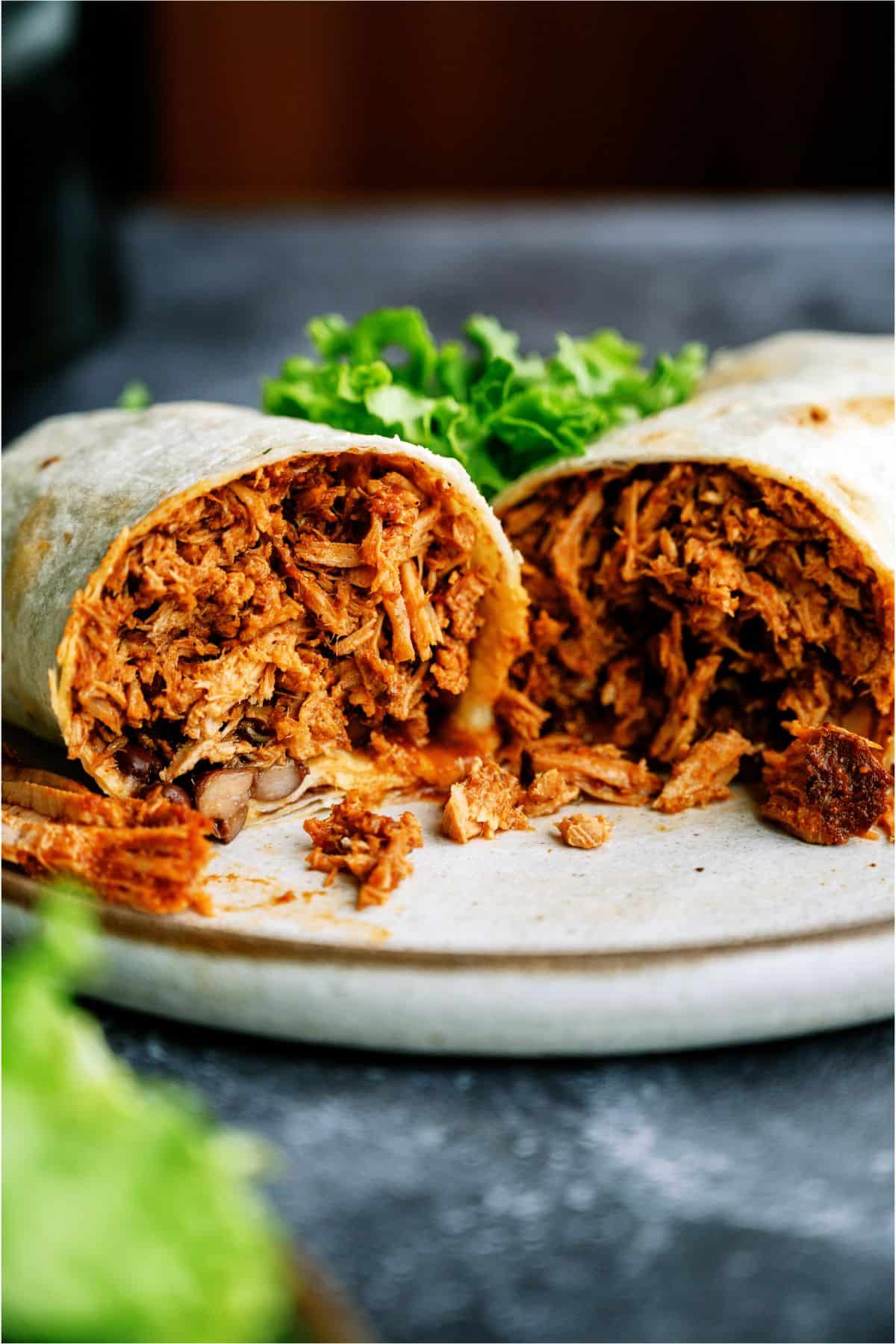 Slow Cooker Mexican Shredded Pork Burrito on a plate cut in half