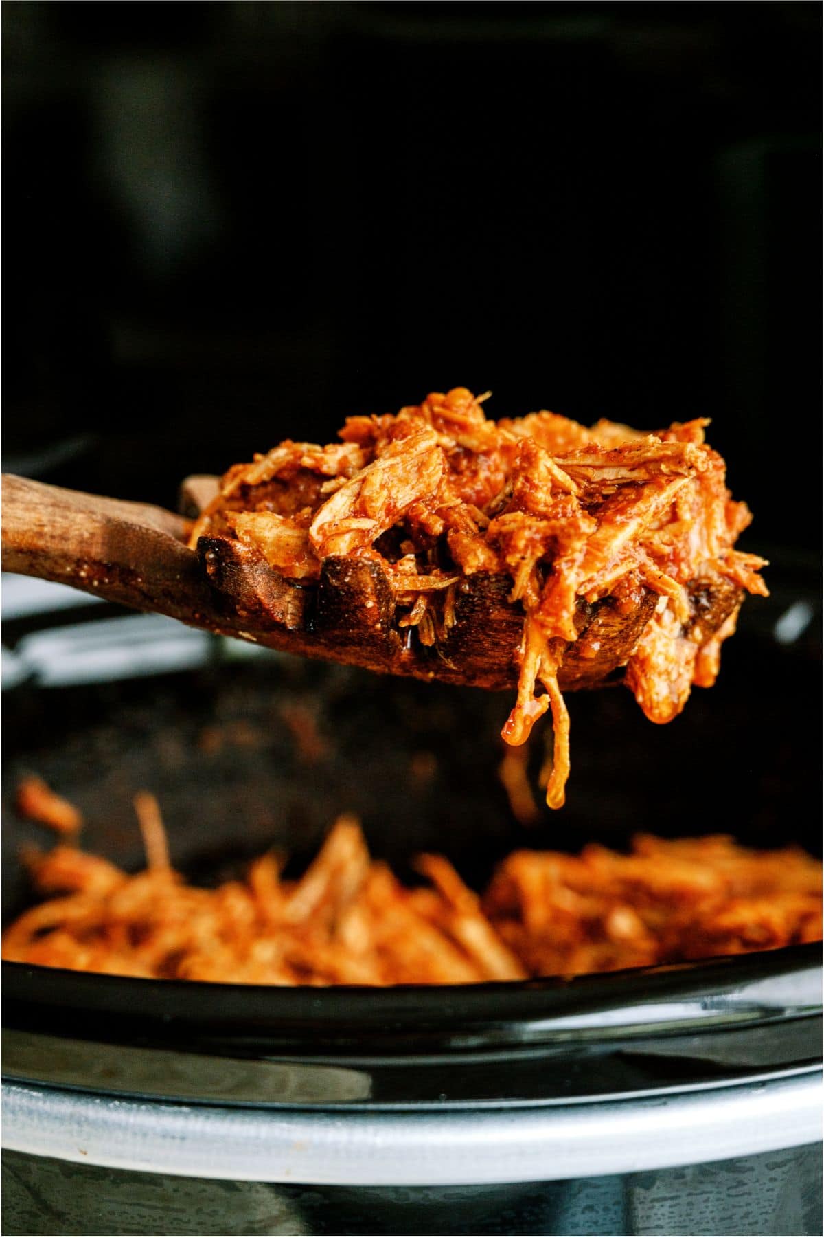 Slow Cooker Mexican Shredded Pork in a slow cooker with a wooden spoon  lifting shredded pork out