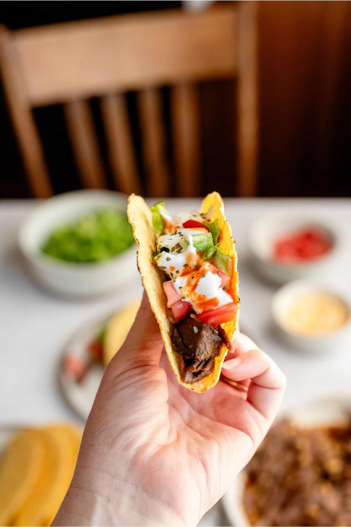 A hand holding up one Slow Cooker Shredded Beef Taco