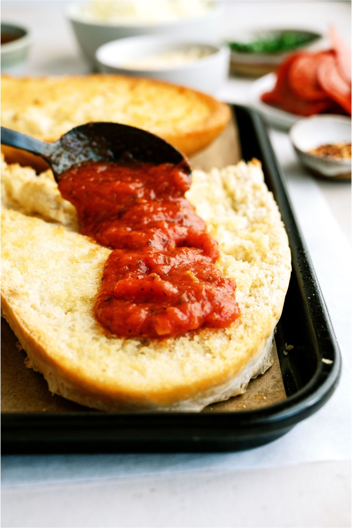 Spreading pizza sauce on a slice of French Bread