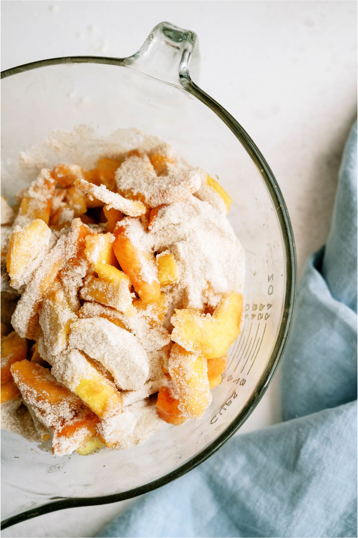 Peaches in mixing bowl with flour mixture sprinkled on top