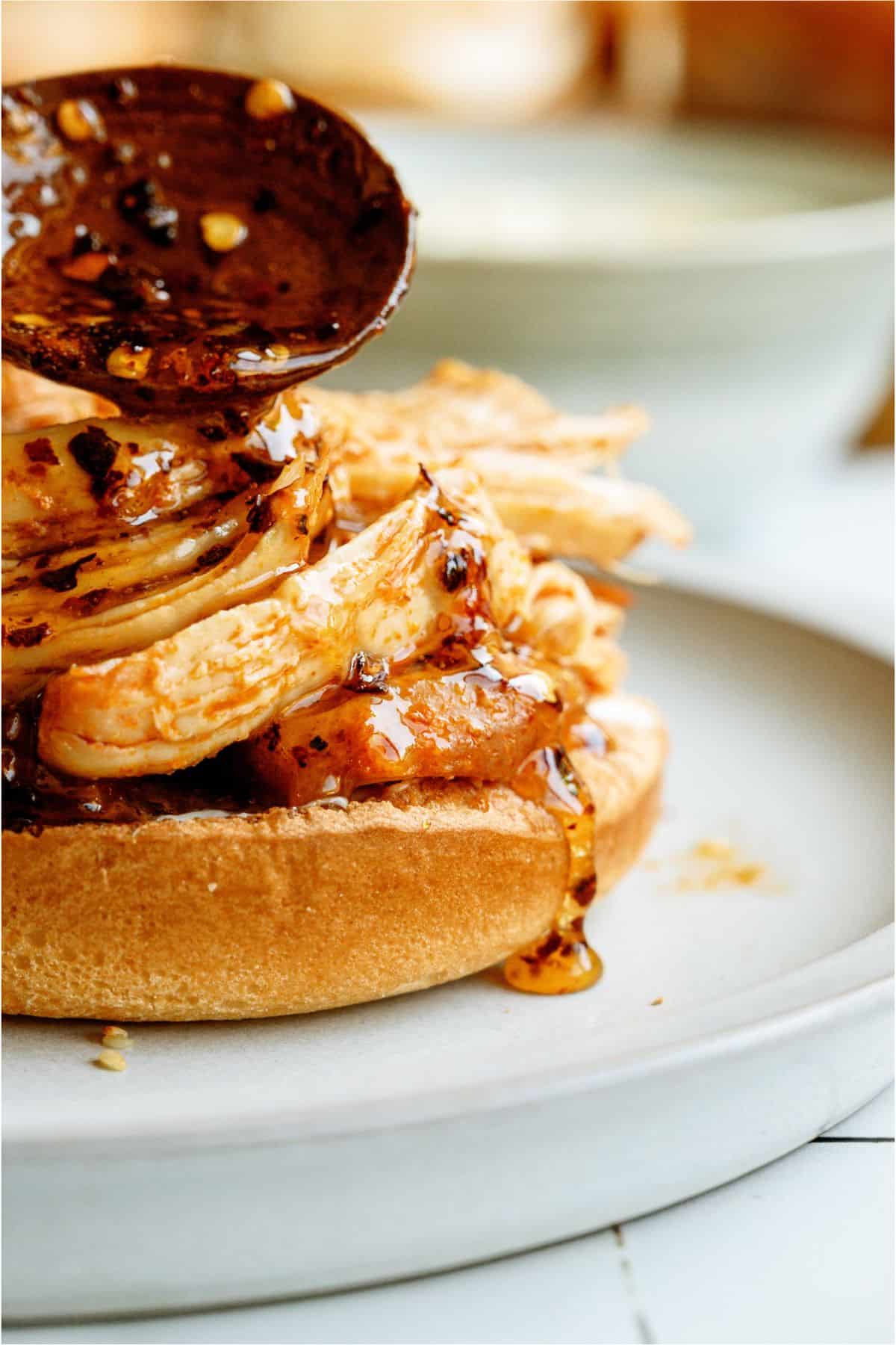 Spooning hot honey sauce on top of an open faced Instant Pot Hot Honey Chicken Sandwich