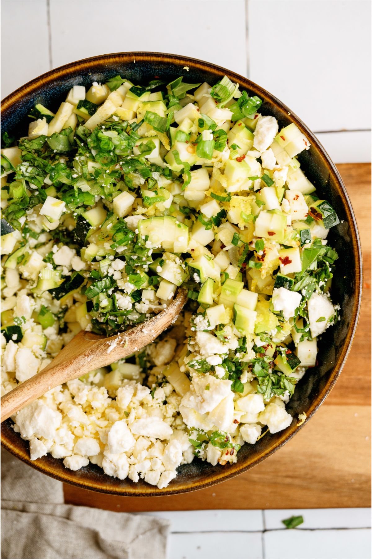 Mixing ingredients for Zucchini Feta Bruschetta in a large bowl