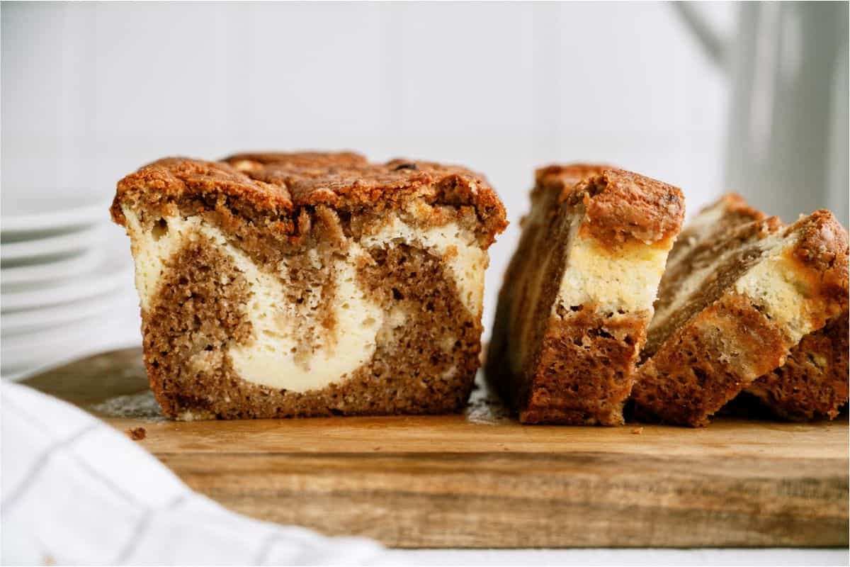 A loaf of Cream Cheese Banana Bread being sliced on a cutting board