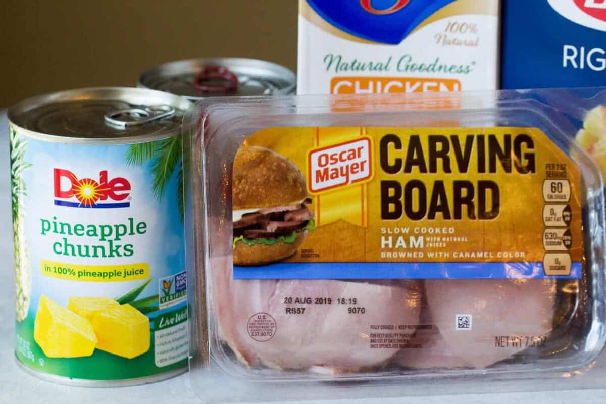 A can of Dole pineapple chunks, a package of Oscar Mayer carving board ham, and a carton of chicken broth.