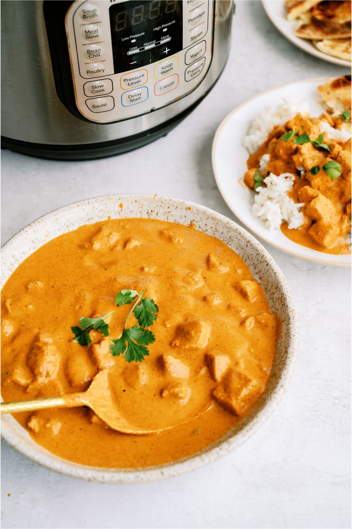 A bowl of Instant Pot Chicken Tikka Masala in front of the Instant Pot