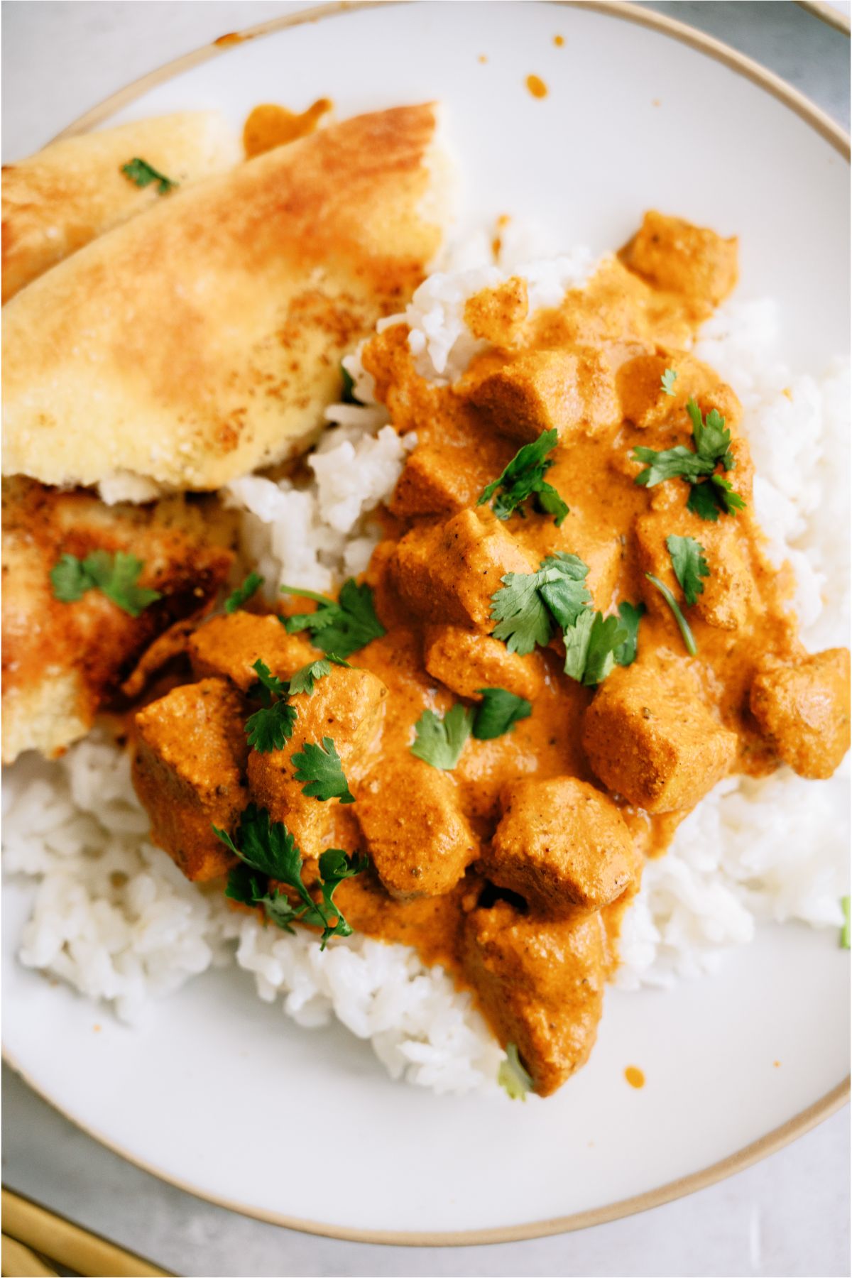 A plate with a serving of Instant Pot Chicken Tikka Masala over rice with Naan Bread
