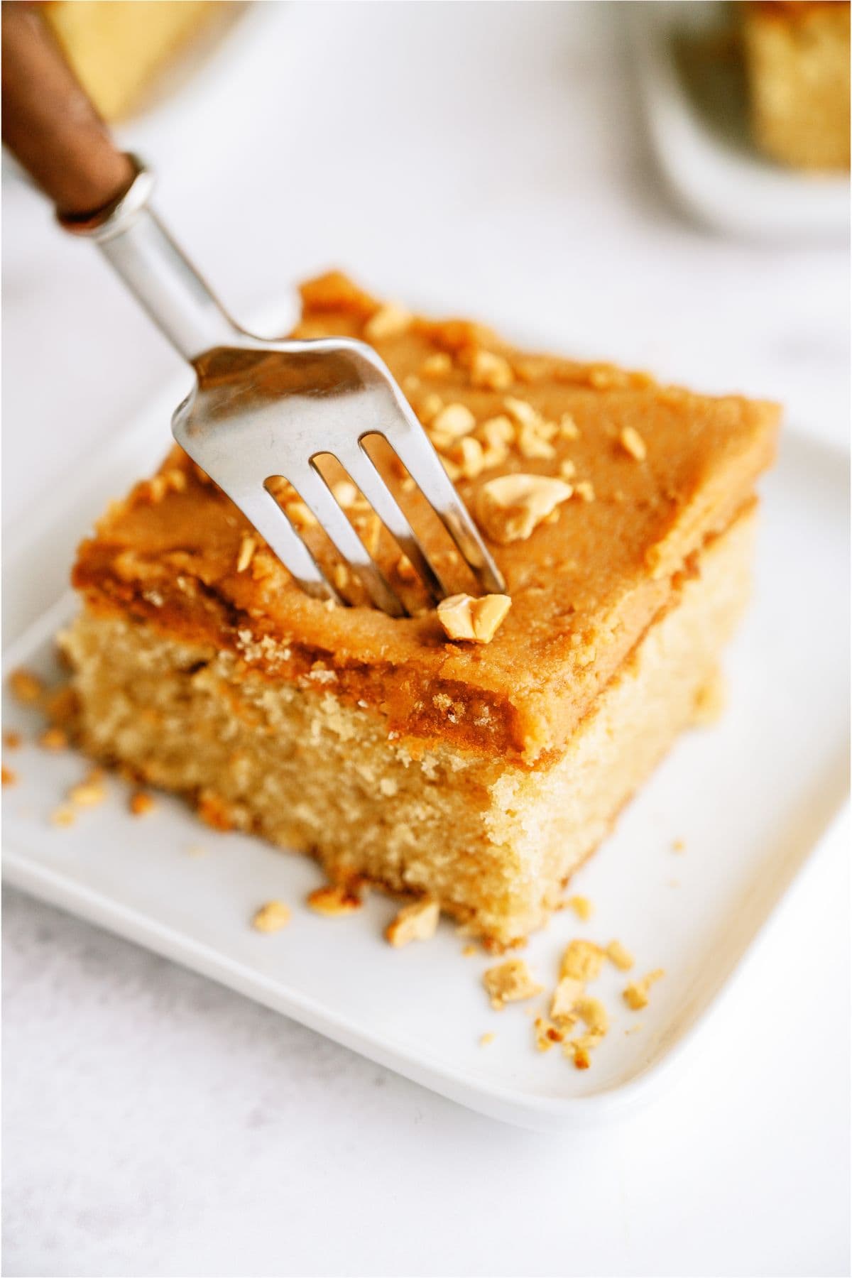 A slice of Peanut Butter Sheet Cake on a plate with a fork in it