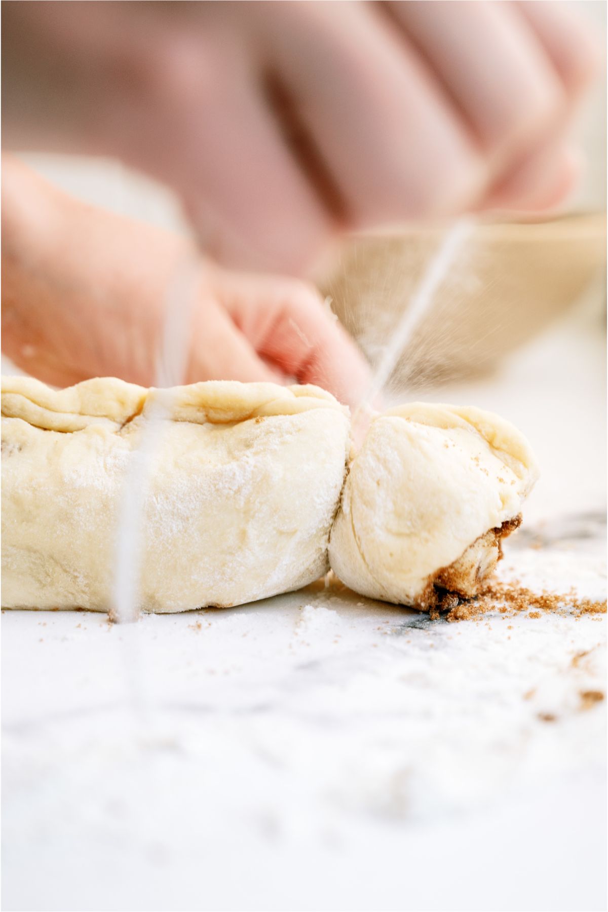 Slicing the The BEST Homemade Cinnamon Rolls dough with dental floss