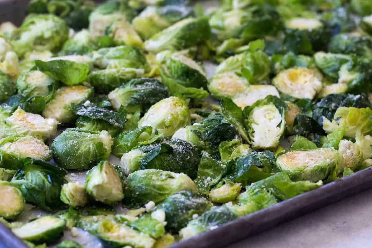 Chopped Brussels sprouts are spread evenly on a baking sheet, prepared for roasting.