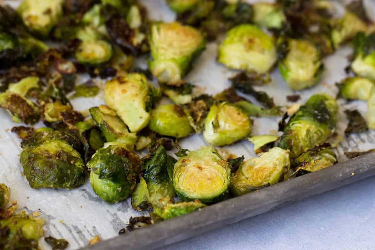 Roasted Brussels sprouts on a parchment-lined baking sheet, with some pieces charred and browned.