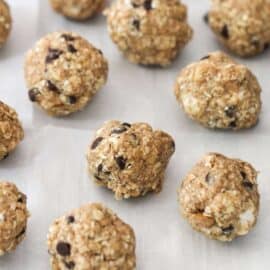 Several oatmeal and chocolate chip energy balls are arranged on a white sheet. A few marshmallows are visible in the background.