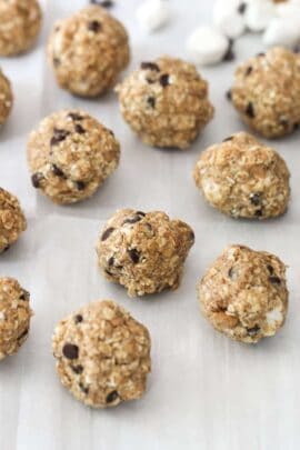 Several oatmeal and chocolate chip energy balls are arranged on a white sheet. A few marshmallows are visible in the background.