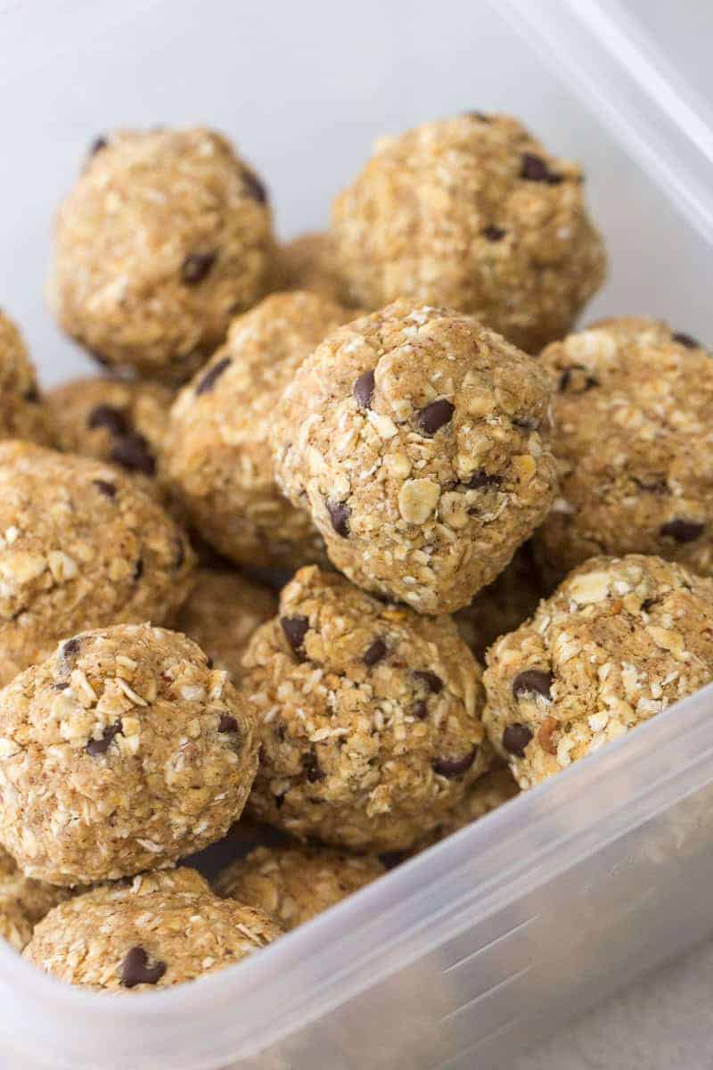 A plastic container filled with several oat and chocolate chip energy balls.