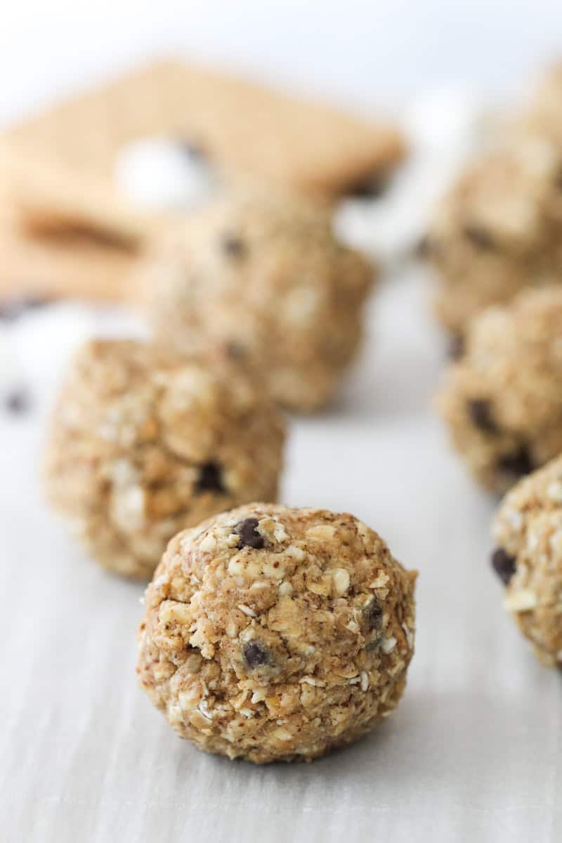 Close-up of several oatmeal energy bites with visible chocolate chips and oats, arranged on a white surface with blurred background.