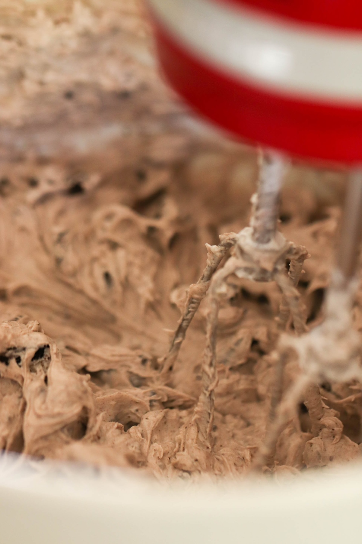 Close-up of an electric mixer with beater attachments blending chocolate batter.