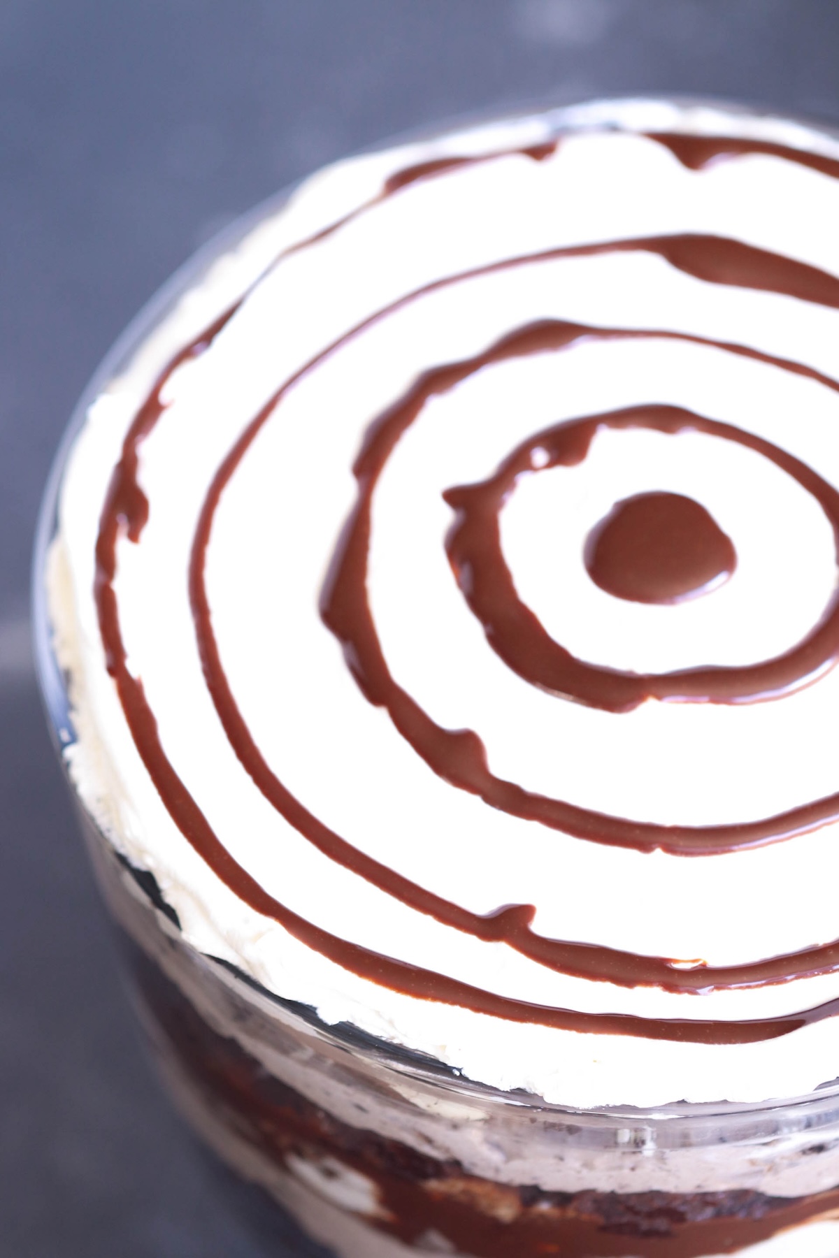 A layered dessert with chocolate and cream topped with concentric circles of chocolate drizzle.