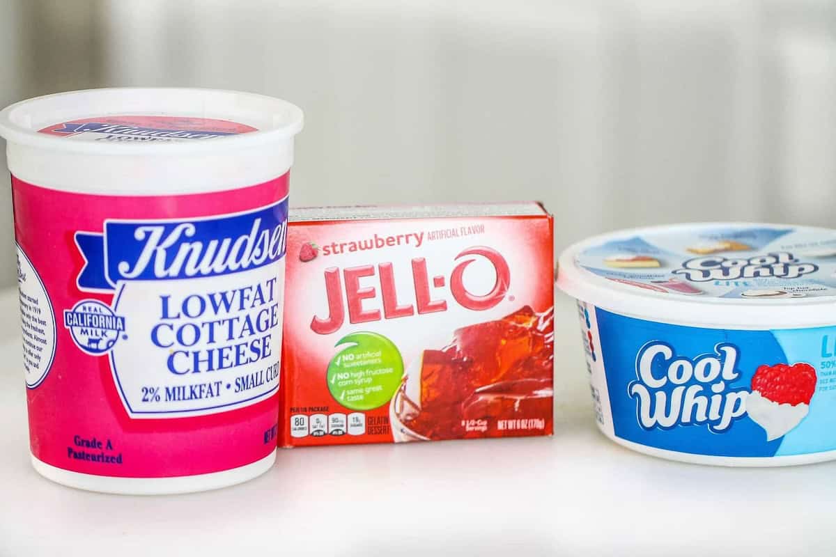 Containers of Knudsen low-fat cottage cheese, Jell-O strawberry gelatin, and Cool Whip whipped topping are placed side by side on a white surface.