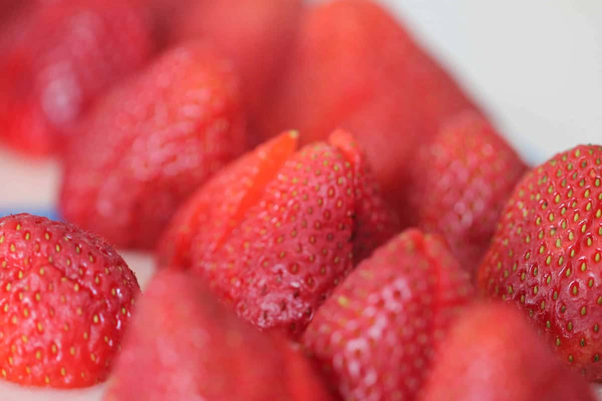 Close-up view of several ripe, red strawberries sliced in half and arranged closely together.