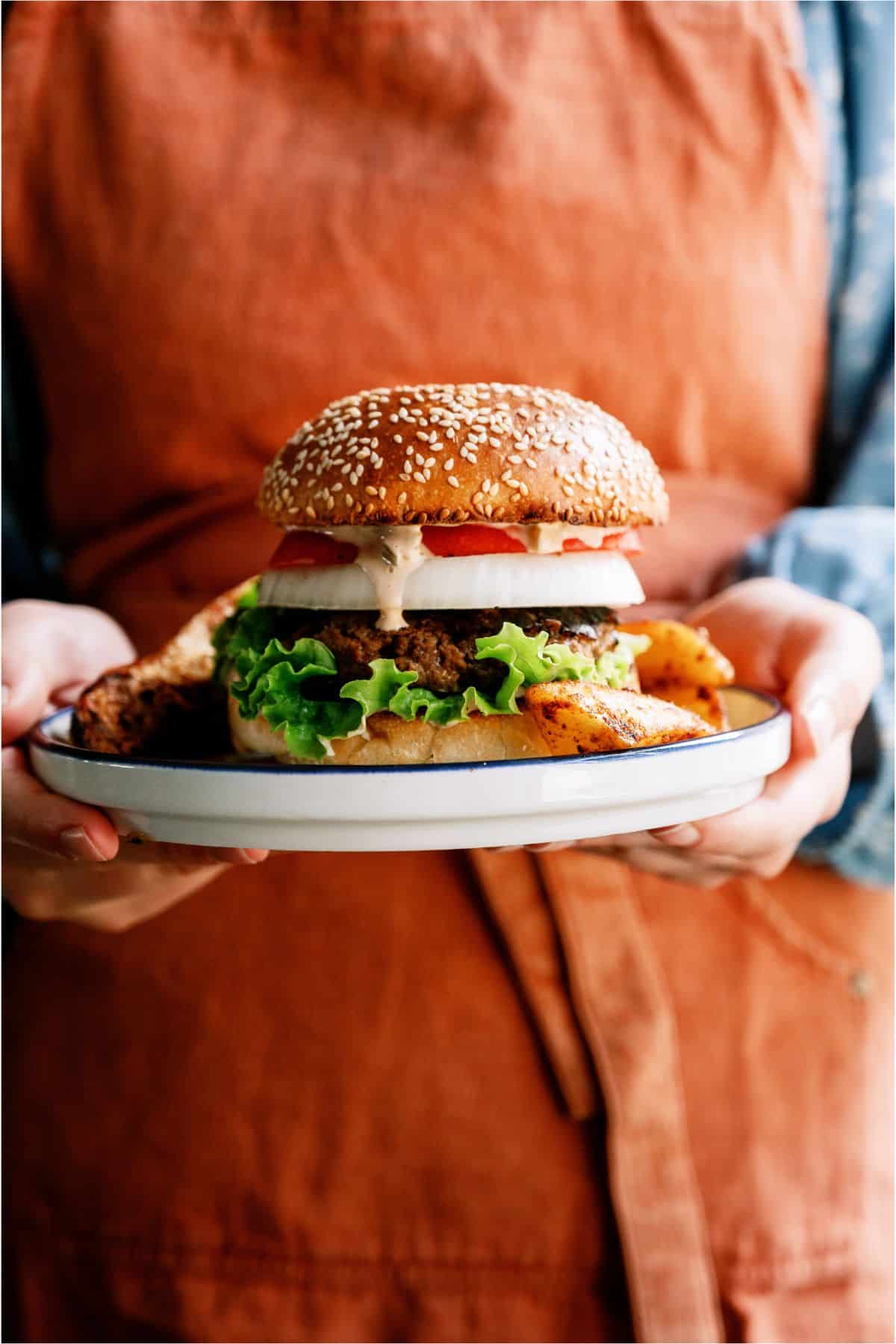 Someone holding a plate with Best Hamburger Recipe With Famous Secret Sauce on it