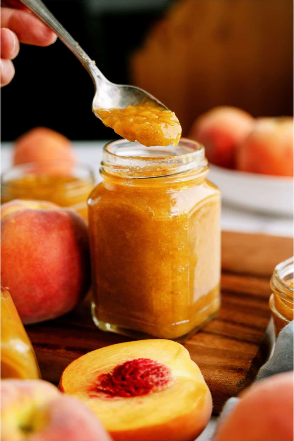 Instant Pot Peach Preserves in a jar with a spoon lifting a spoonful out