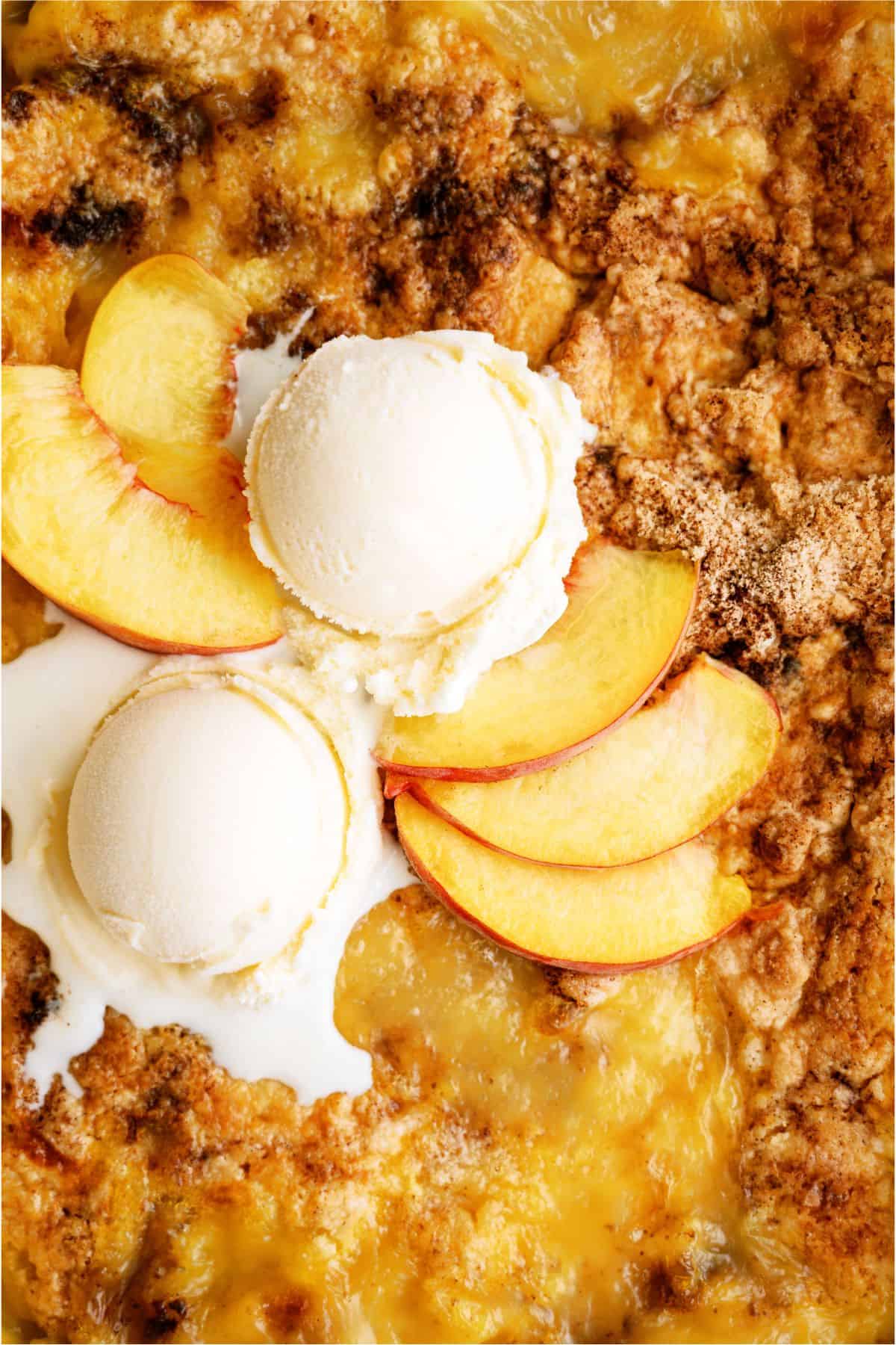 Close up of Peach Cobbler Dump Cake (4 Ingredients) in baking dish with ice cream on top