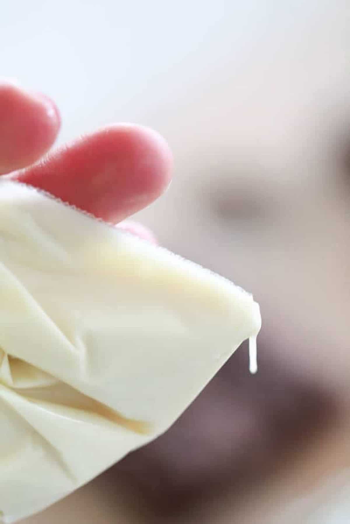 Close-up of a hand holding a thin film of icing.