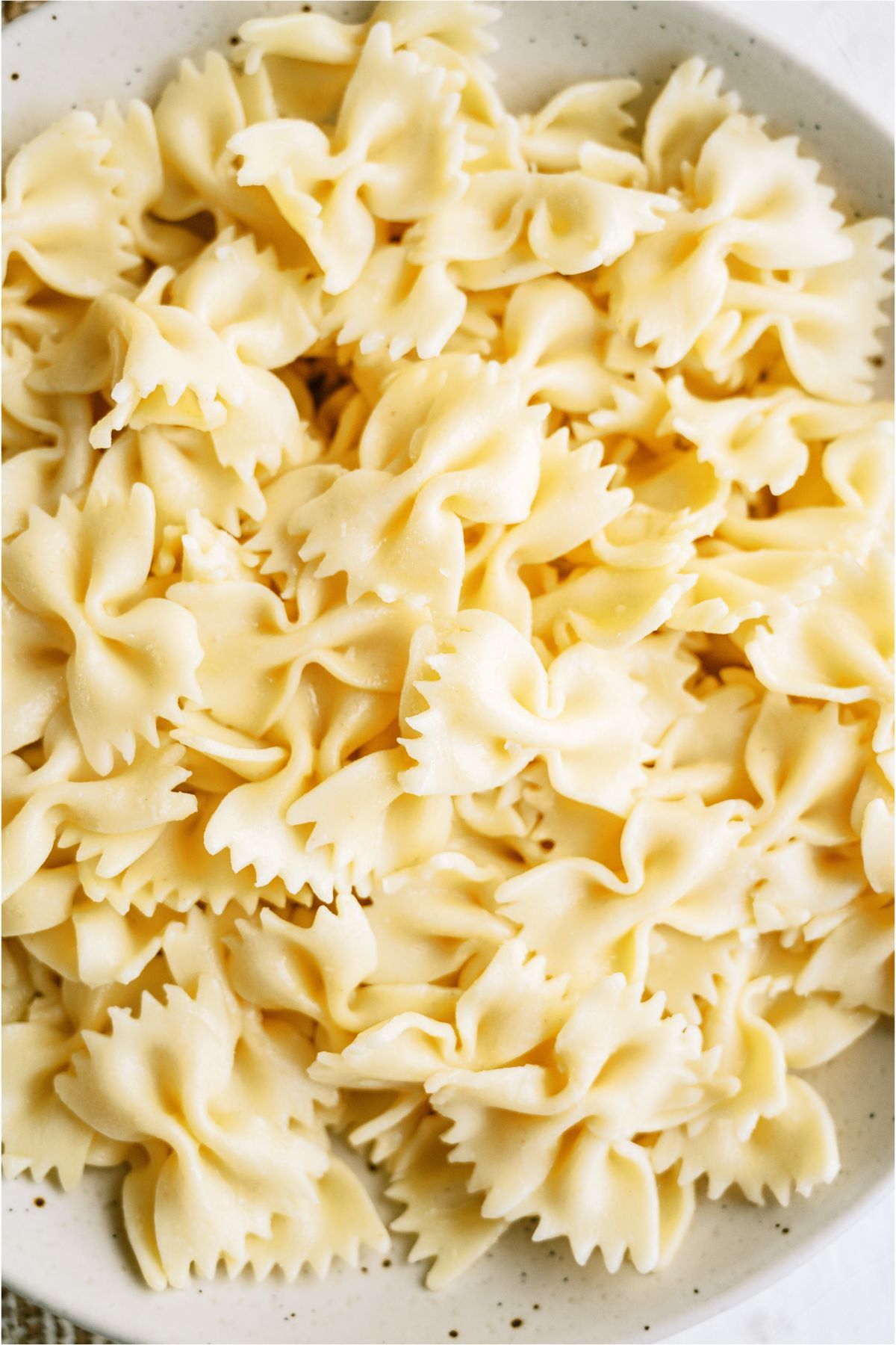 A plate full of cooked bowtie pasta noodles.