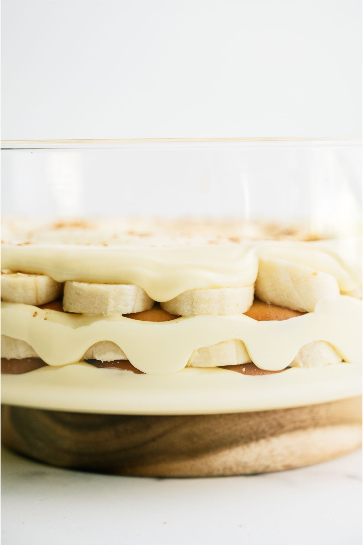 Large glass bowl showing layers of pudding, nilla wafers and bananas repeated.