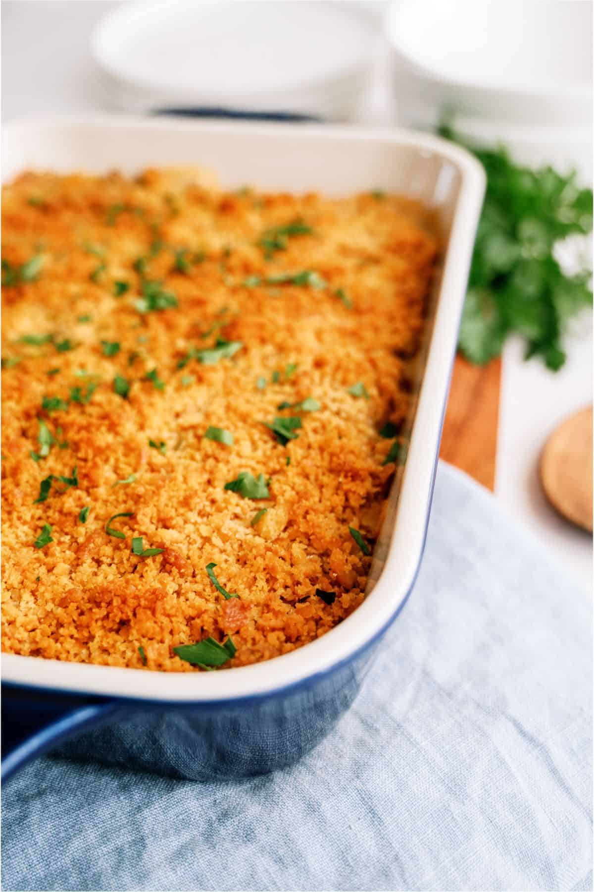 A casserole dish filled with crack chicken casserole topped with golden breadcrumbs and garnished with chopped parsley.