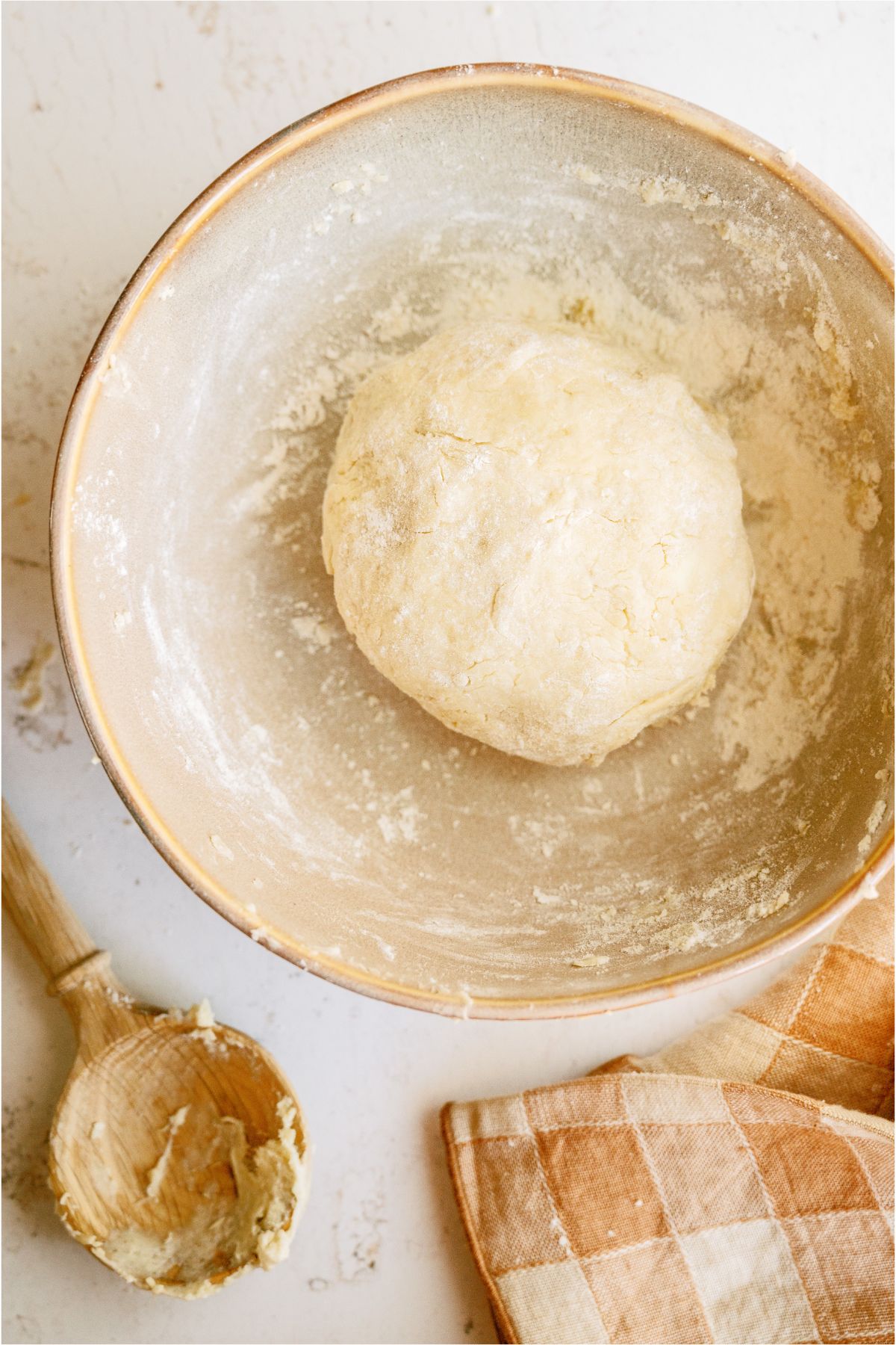 A mixing bowl with pie crust dough rolled into a ball inside of it. 