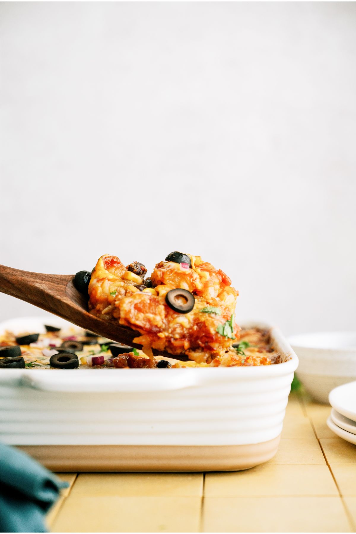 A wooden spoon scooping out a serving of Mexican Tater Tot Casserole