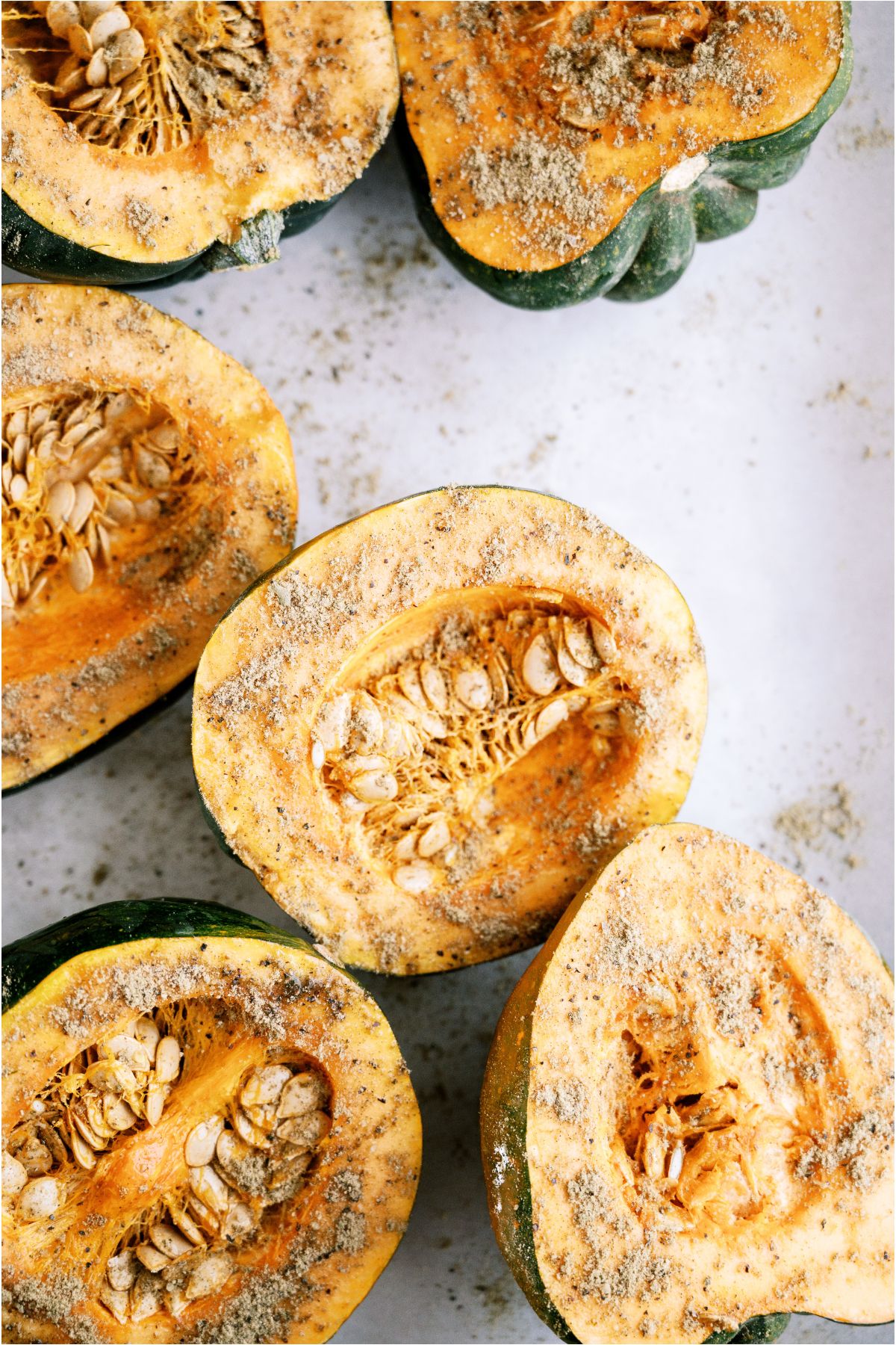 Several Acorn squash cut in half and seasoned.