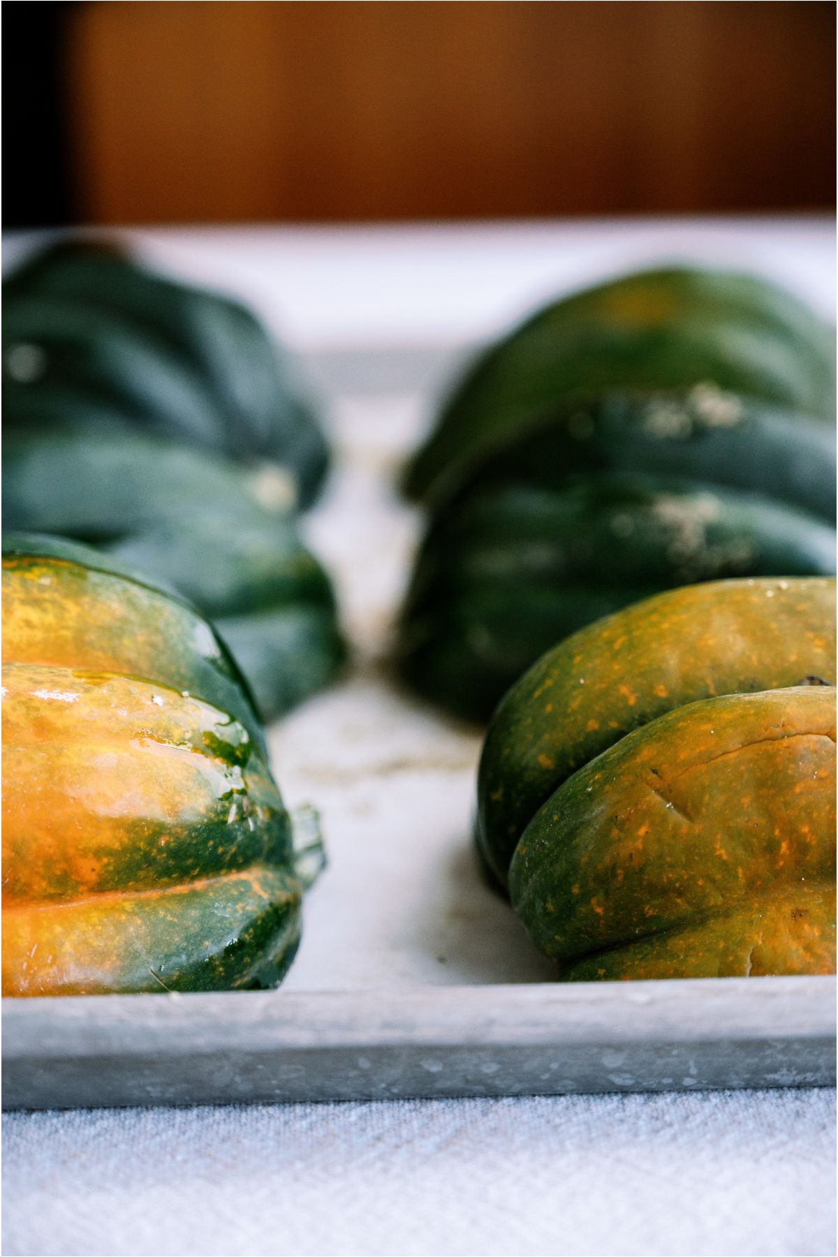 Acorn squash face down on a baking sheet covered in parchment paper.