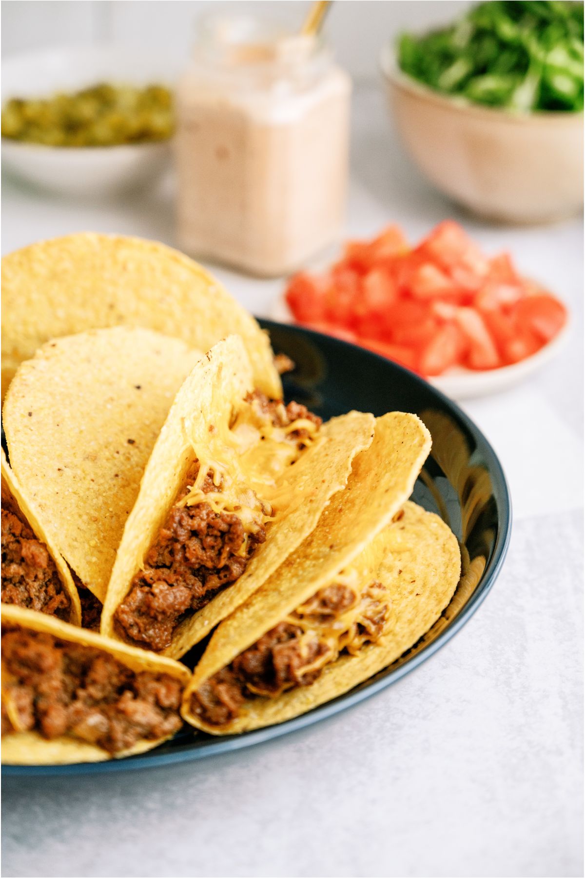 Cheeseburger Tacos on a blue plate topped with cheese.