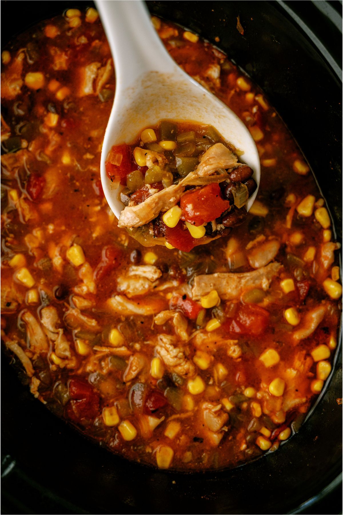 Easy Crock Pot Chicken Tortilla Soup inside the slow cooker with a white ladle lifting a scoop out.